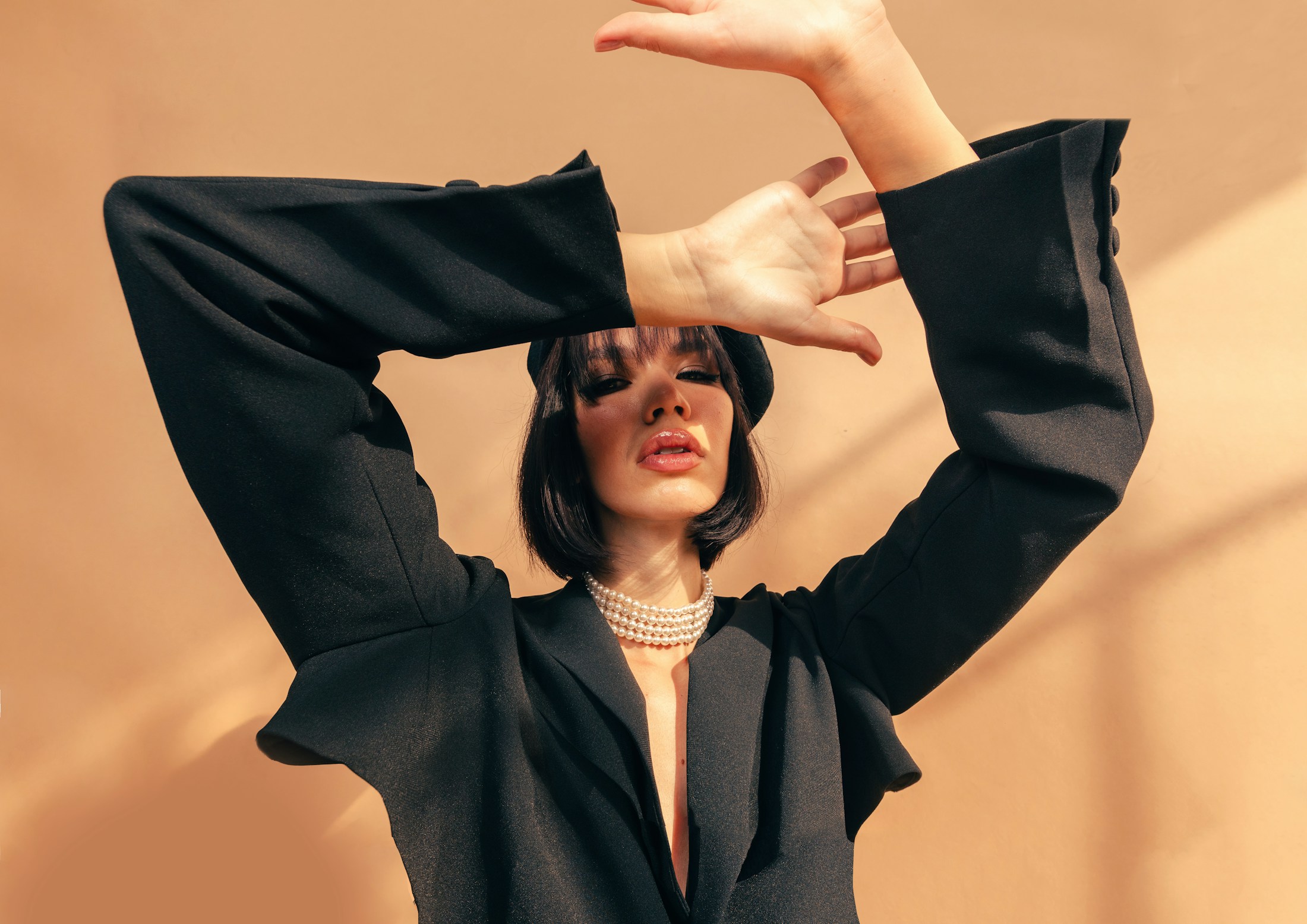 Editorial portrait styled with a black blazer and pearl necklace.