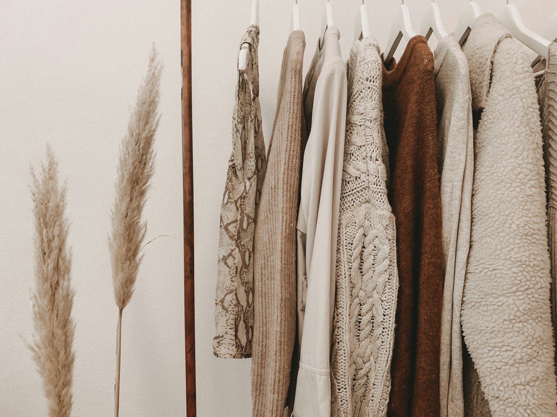 Neutral clothing rack with soft garments and warm studio styling.